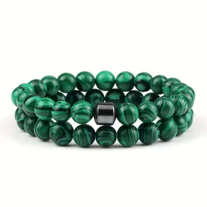 Green malachite beaded bracelet set with black square stone accent on white background
