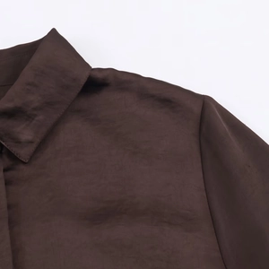 Dettaglio ravvicinato del colletto della camicia di raso marrone con cuciture e trama liscia