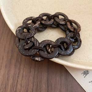 Macro detail of dark brown coconut shell beads with natural wood grain and elastic cord