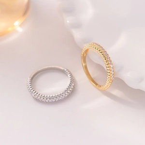 Minimalist gold and silver rings with rows of shimmering zircon stones on a white tray
