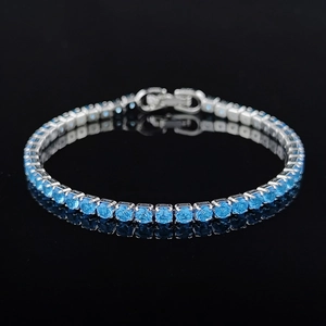 Macro shot of silver tennis bracelet with round cut light blue zircons on black background