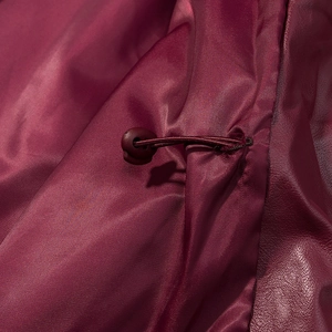 Detailed close-up of burgundy leather jacket lining with drawstring and plastic cord lock