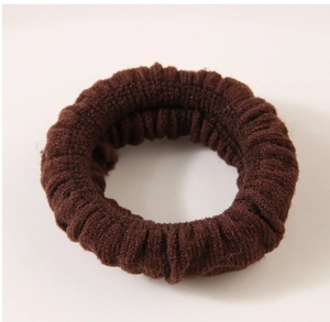 Detail of a dark brown elastic knitted hair tie with a ribbed texture and durable stretch