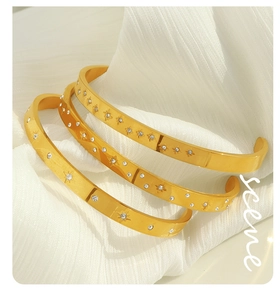 Detail of three-piece 18K gold plated bangle set with star engravings and zircon stones