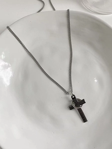 Close-up of stainless steel cross pendant with engraved Spanish text and ring detail