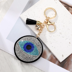 Macro detail of Evil Eye keychain with sparkling rhinestones, gold hardware, and black tassel