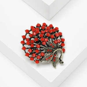 Detailed macro view of vintage Turkish berry brooch with red rhinestones and antique silver leaves