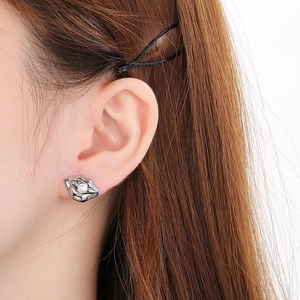 Close-up of silver lip-shaped stud earring with a white pearl on a female ear