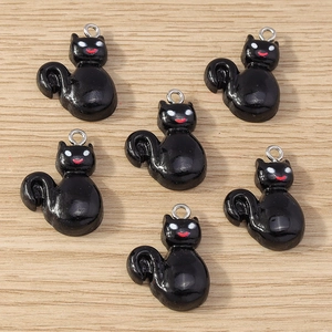 Detail of six black resin cat charms with metal rings on light wood background