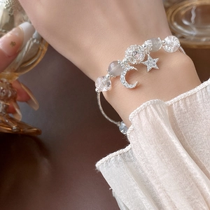 Star and moon charm bracelet with clear crystals and zircon beads on woman's wrist