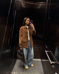 Mirror selfie showing brown faux suede jacket detail with flap pockets and buttons