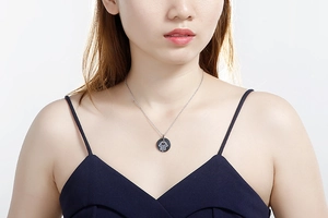 Detailed close-up of a silver Hamsa Hand pendant necklace with crystals on a model