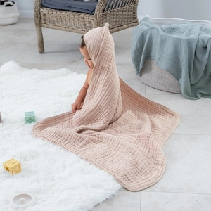 Close-up of pink 6-layer muslin cotton hooded baby towel on soft white carpet