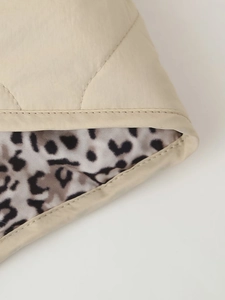 Detail of beige quilted jacket featuring leopard print lining and premium stitching