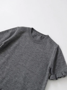 Detail of grey knitted short sleeve top with ruffled cuffs and round neckline