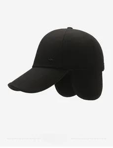 Detail of black winter baseball cap featuring warm ear flaps and metal brand plaque