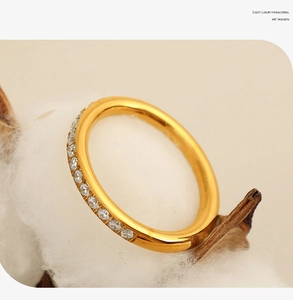 Close-up of a gold ring with sparkling cubic zirconia on dried leaves and cotton