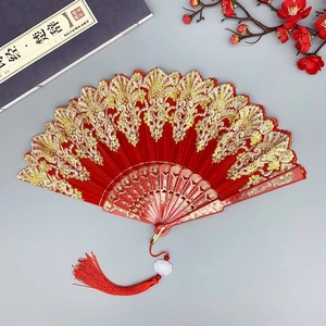 Red Chinese folding fan with gold embroidery, red tassel and cultural props