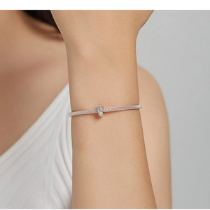 Silver mesh bracelet with circular charm detail on wrist for a minimalist modern look