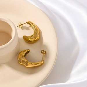 French vintage gold C-shape pleated hoop earrings with textured finish on ceramic plate
