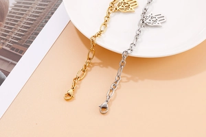 Detail of gold and silver Hamsa Hand bracelets with hollowed patterns and lobster clasp