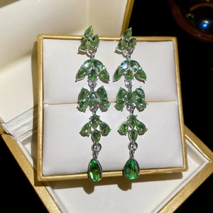 Détail de boucles d'oreilles pendantes en cristal vert sur un support à bijoux