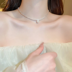 Close-up of elegant pearl pendant necklace worn on neck featuring silver braided chain