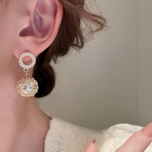 Detail of vintage gold earrings with hollow spheres, pearls, and crystals on a model