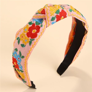 Detailed embroidery texture on pink fabric knotted headband with colorful floral patterns