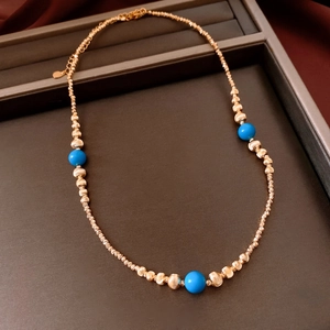 Vue détaillée du collier perlé plaqué or 18 carats avec pierres bleues dans son écrin
