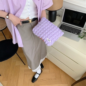 Detail of a purple quilted puffy toiletry bag with texture held by a person