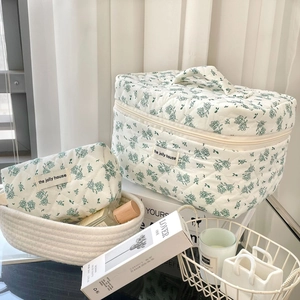Detailed set of two green floral quilted cosmetic bags on a bright professional background
