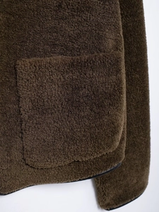 Detailed view of dark brown fleece texture and pocket stitching on this stylish jacket