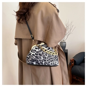Detail of leopard print shell bag with gold chain decoration on model wearing a trench coat