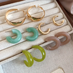 Detail view of colorful acrylic and gold hoop earrings set on a velvet jewelry tray