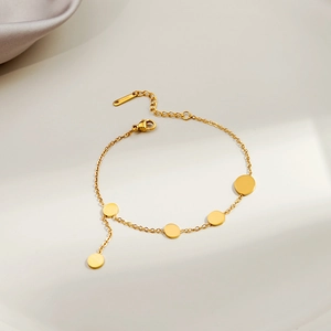 Close-up of a minimalist gold bracelet with five polished round discs and a lobster clasp