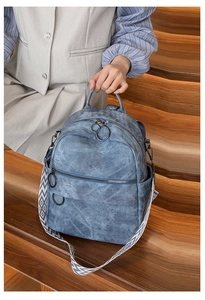 Dettaglio dello zaino in denim blu con anello metallico e ampia tracolla geometrica