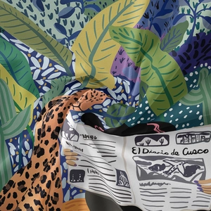 Close-up of bohemian tapestry fabric with tropical leaves, leopard print and newsprint design