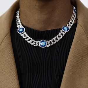 Detailed view of silver Cuban link necklace with blue evil eye pendant on a model