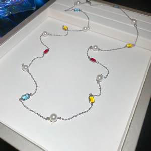 Detail view of pearl and multicolored gemstone necklace in an elegant jewelry box