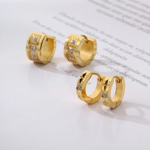 Close-up of gold plated stainless steel C-shaped hoop earrings with zircon on a book