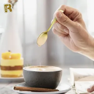 Close-up of elegant gold-plated mini dessert spoon held over a tiramisu cake
