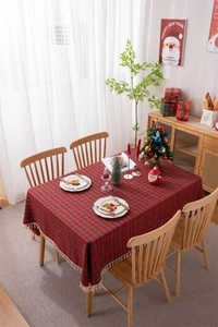 Close-up of red and green plaid Christmas tablecloth featuring beige tassel fringe detail