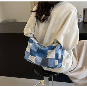 Détail du sac bandoulière en patchwork de denim bleu avec motif à carreaux sur le modèle