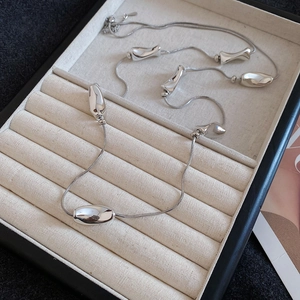 Macro view of silver snake chain necklace with irregular metallic beads in jewelry box