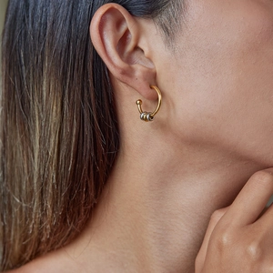 Detailed close-up of mixed metal gold and silver rings on a C-shaped gold hoop earring
