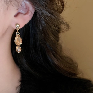 Close-up of elegant gold drop earrings with teardrop crystals worn by a model