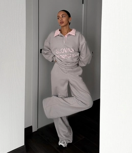 Détail du sweat gris avec broderie col rose et pantalon de sport large