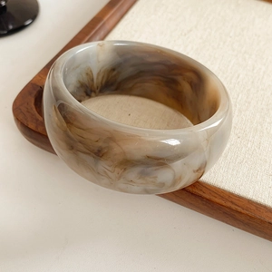 Detailed view of wide amber marble resin bangle with polished tortoiseshell texture
