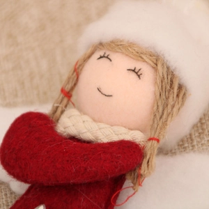Detail of handcrafted fabric angel ornament with knitted textures and embroidery